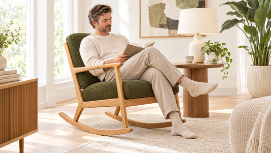 Man reading in a mid century modern rocking chair next to a walnut side table and ceramic lamp