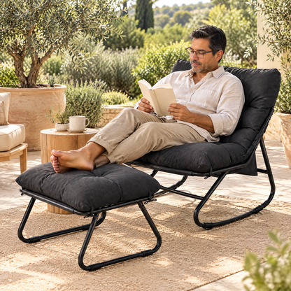 A Latino man with glasses and short dark hair in his early 50s, reading a paperback, in The Tidewater outdoor rocker + ottoman in a sunny stone patio